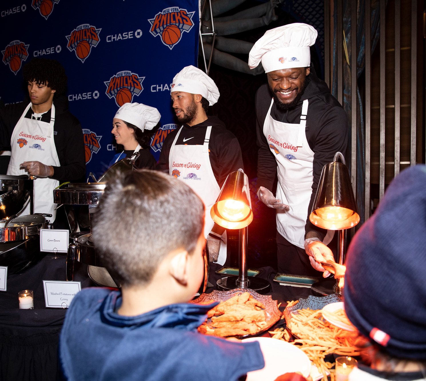 Marcus Camby, Jalen Brunson, and Juluis Randle serve dinner at the annual Knicks Holiday Dinner